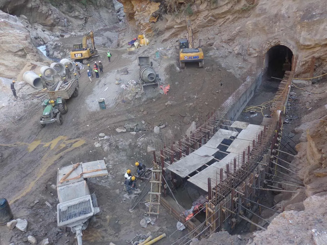 Aerial view of the construction site — formwork, rebar, and excavators at the riverbank