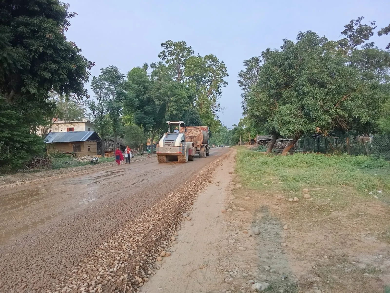 Rural stretch of the highway package mid-grading, trees lining both sides