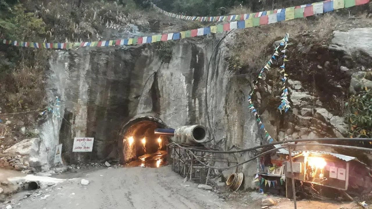 Tunnel portal at the Super Dordi site, strung with prayer flags, lit from within